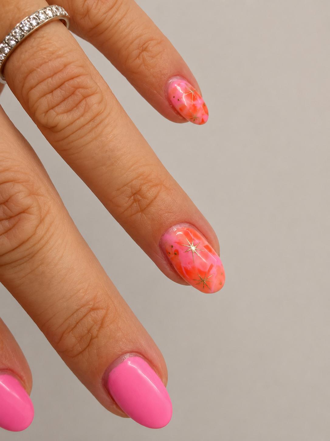 Pink and orange marble nail art with gold stars
