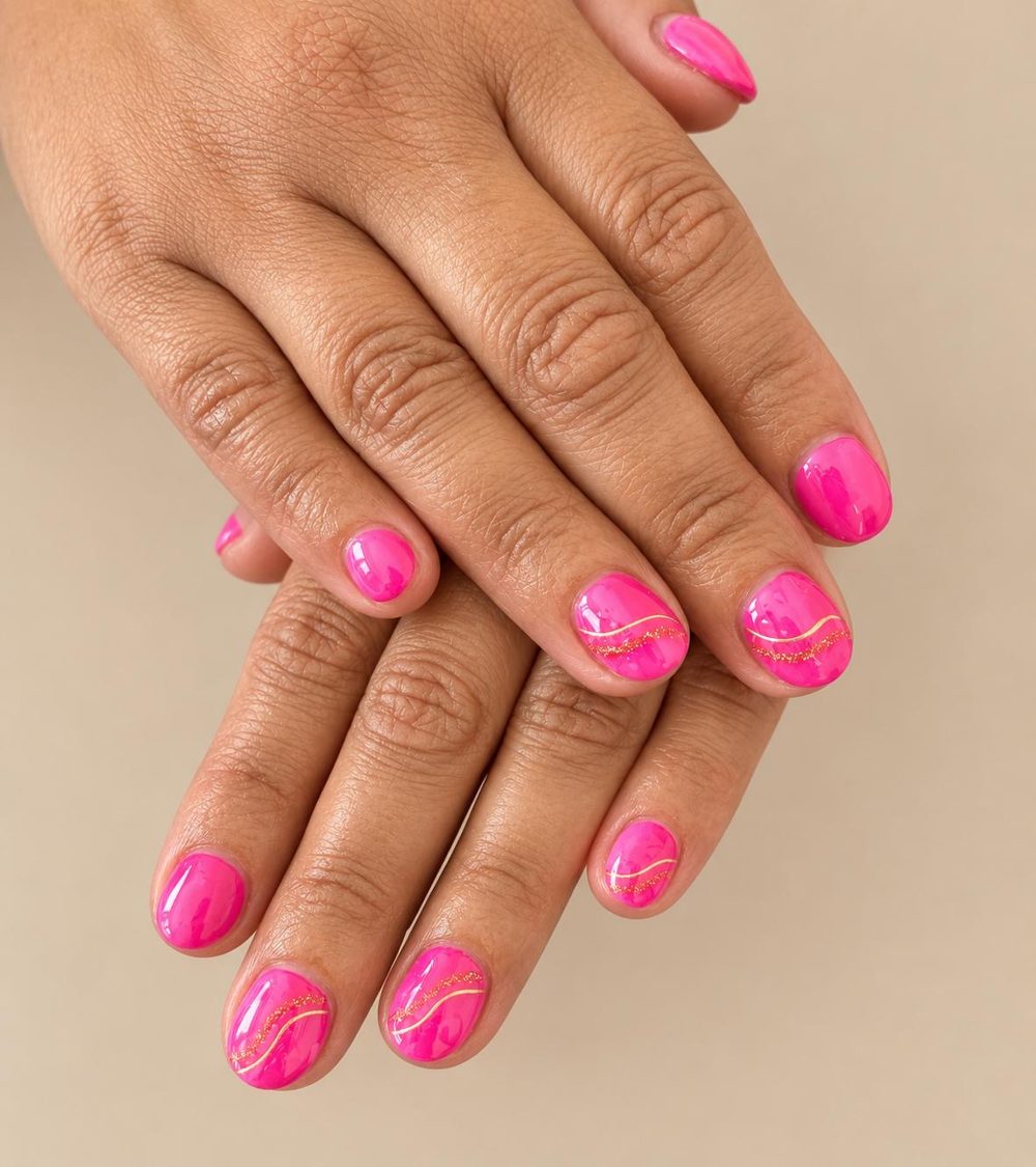 Hot pink gel nails with gold swirl detail